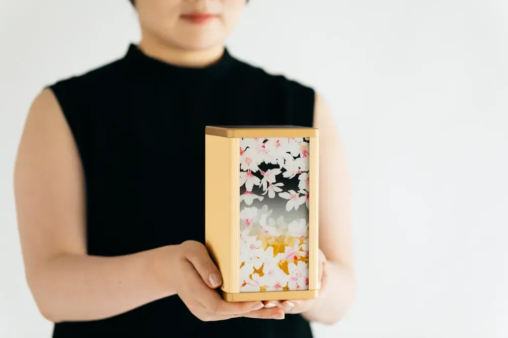 桜の絵柄の骨壺を両手で持つ様子